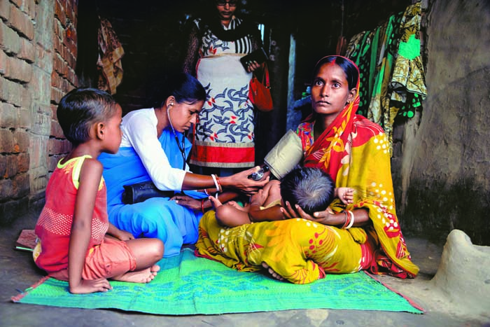 A Swasthya Sahayika (SS) checks the blood pressure of a young mother